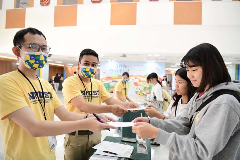 foreigner student being ground staff giving the boarding pass to Taiwanese students